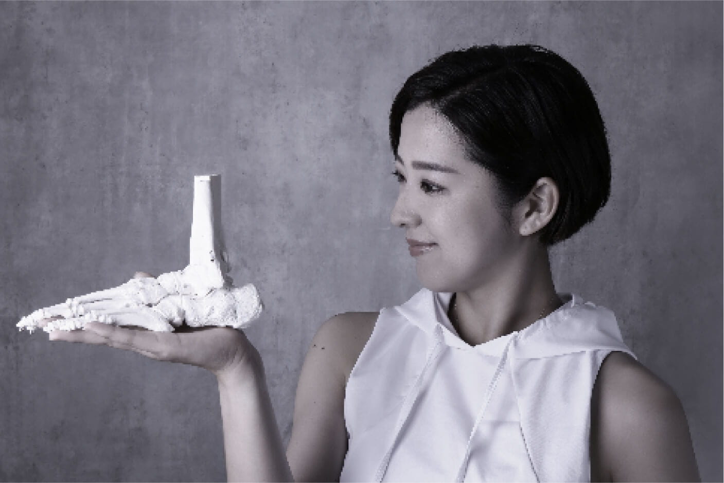 足の模型を手に乗せている女性